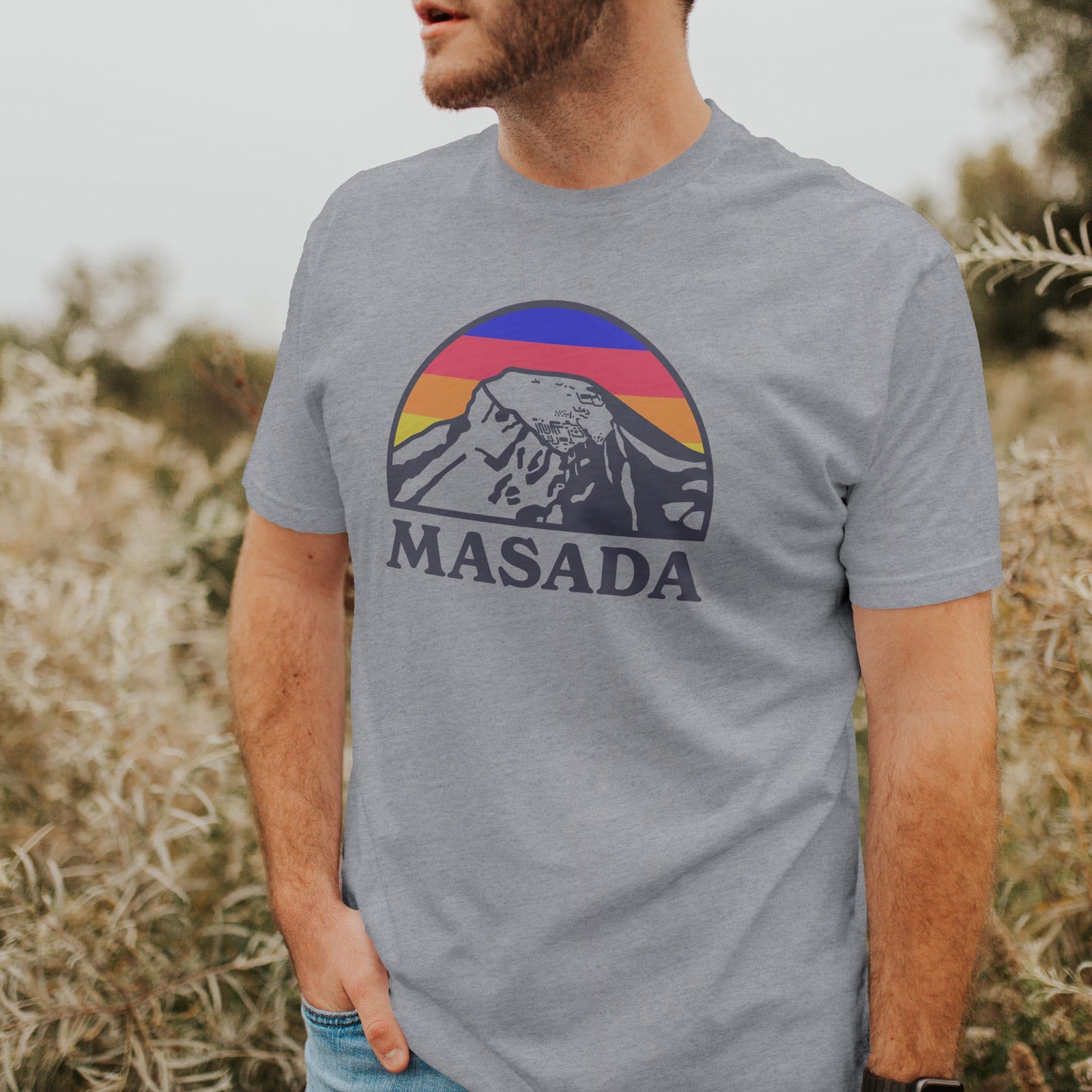 male model in a field, wearing a t-shirt with an illustration of the Masada national park in southern Israel
